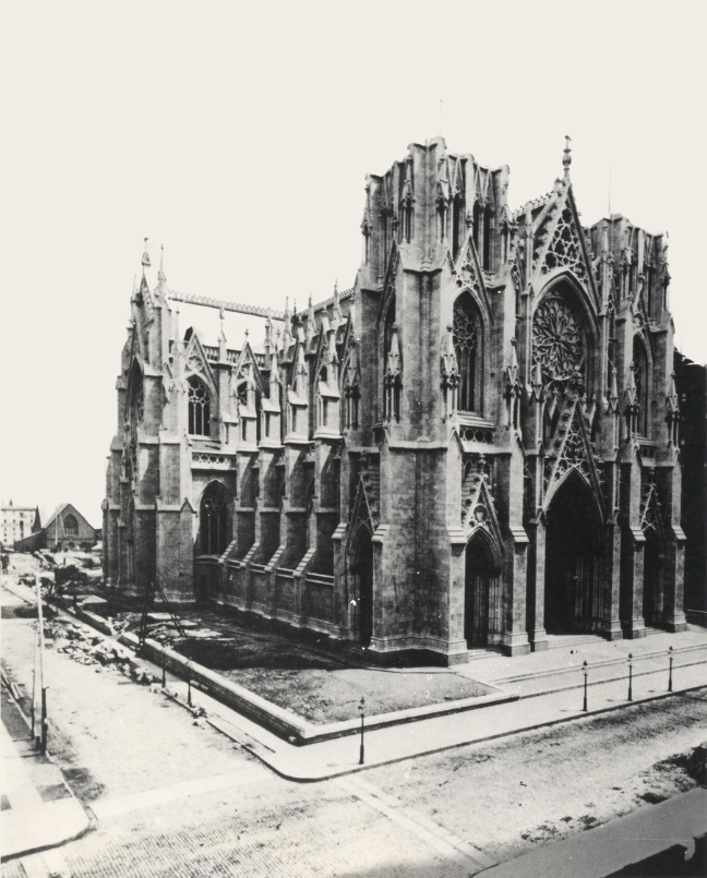 A black and white photograph of the construction of St Patrick's Cathedral, New York. The building is half-formed. 