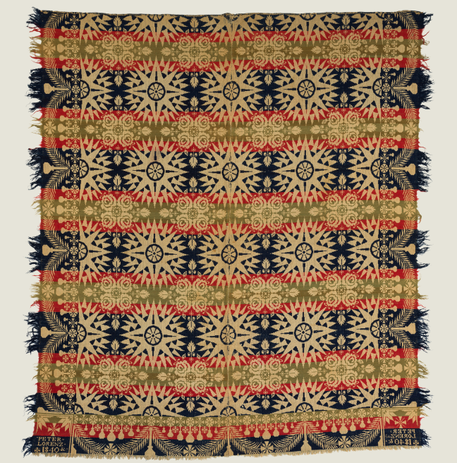 A large woven coverlet with circle and cross patterns in green, red, blue, and cream. 