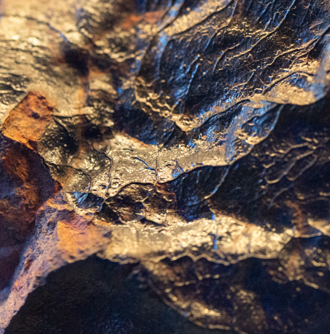 A close up of a meteorite with a wave-like surface with rims and edges.