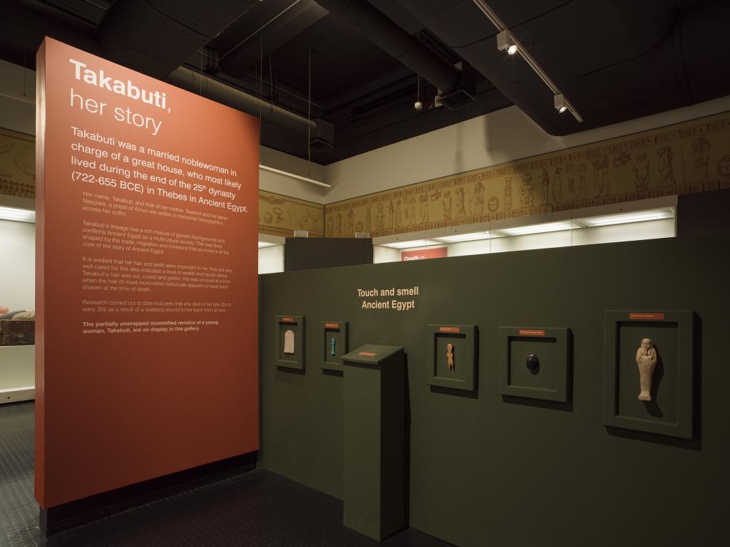 A photograph of the Ancient Egypt gallery at the Ulster Museum, showing a large introductory panel and some interactive elements.