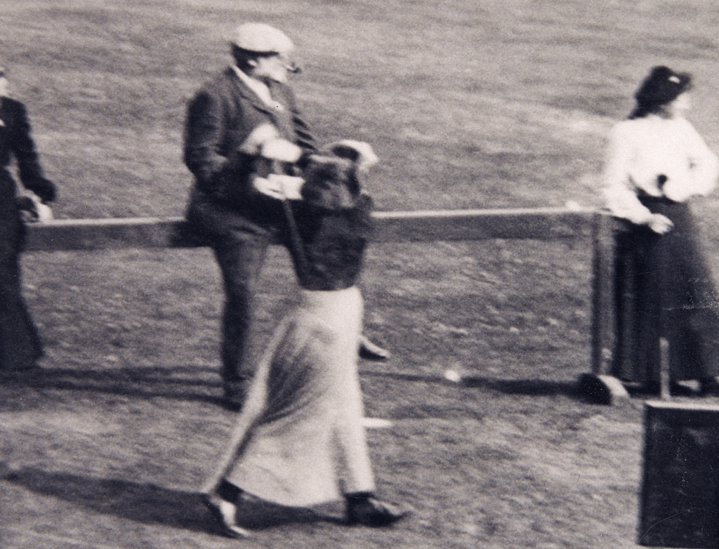 A black and white photograph of a woman walking onto a golf course.