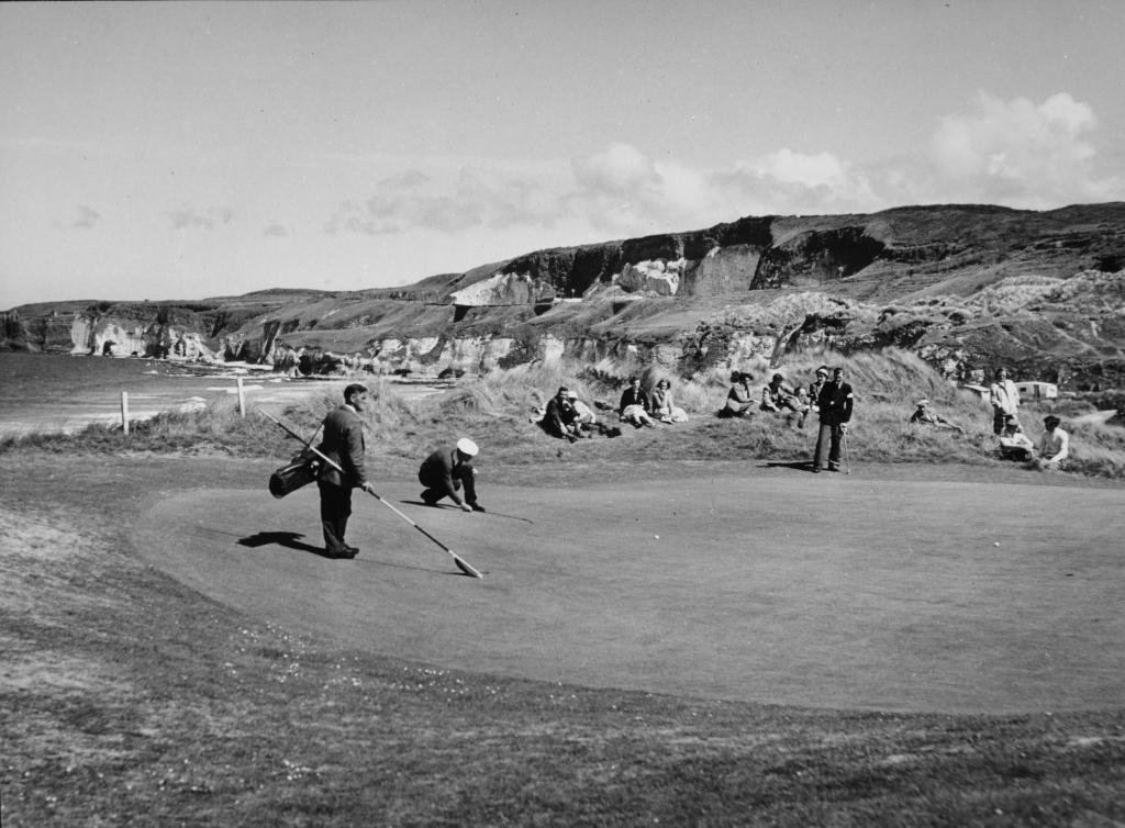 A black and white photograph of a group of men playing a round of golf at Royal Portrush Golf Course.
