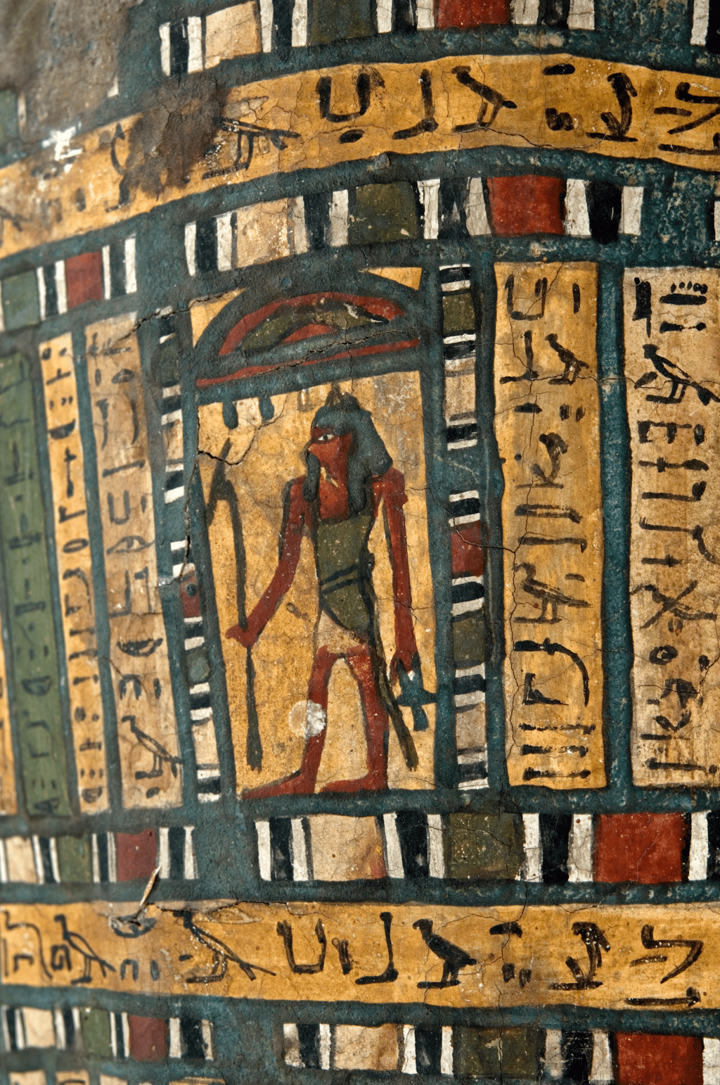A photograph of Takabuti's coffin showing an image of a protective God and the name 'Takabuti' written in multiple ways in hieroglyphs.