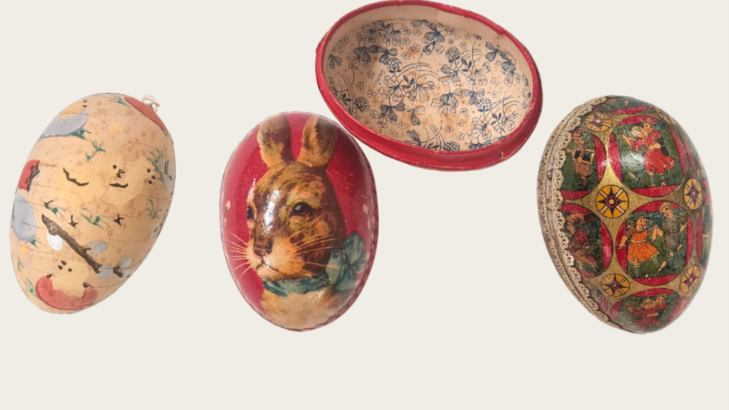 A series of three cardboard eggs for holding easter treats. The first is decorated with chicks; the second has the face of a rabbit; the third has little motifs of children playing.