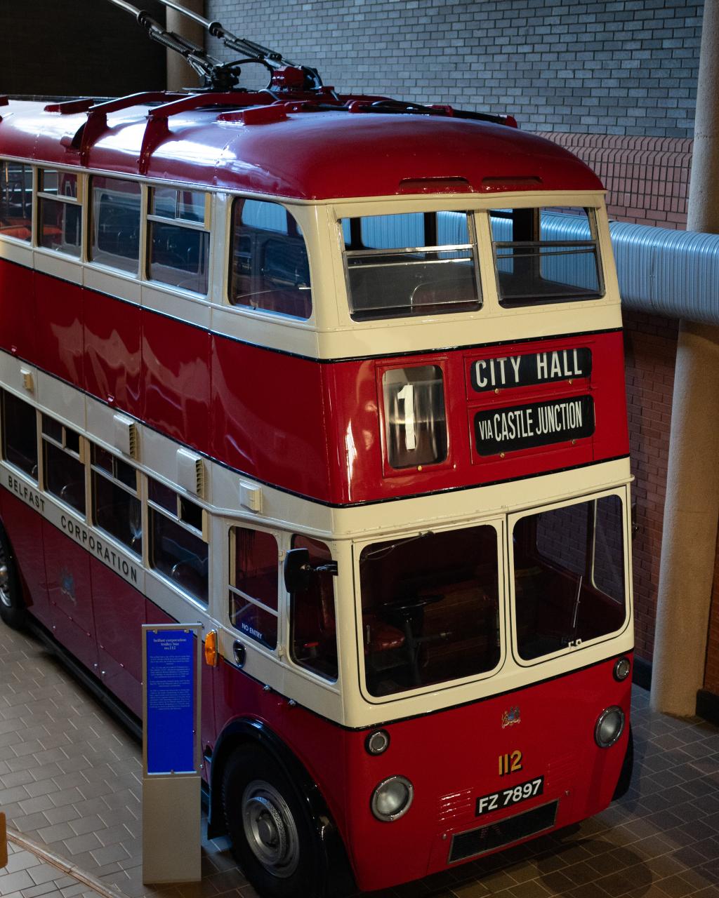 A red and white trolleybus in a museum gallery.