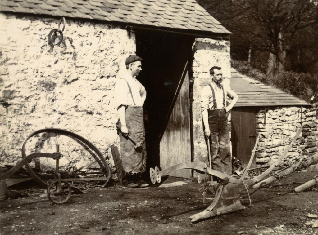 two blacksmiths standing outside forge