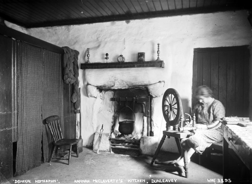 An interior shot with a woman on the right with a spinning wheel in a kitchen