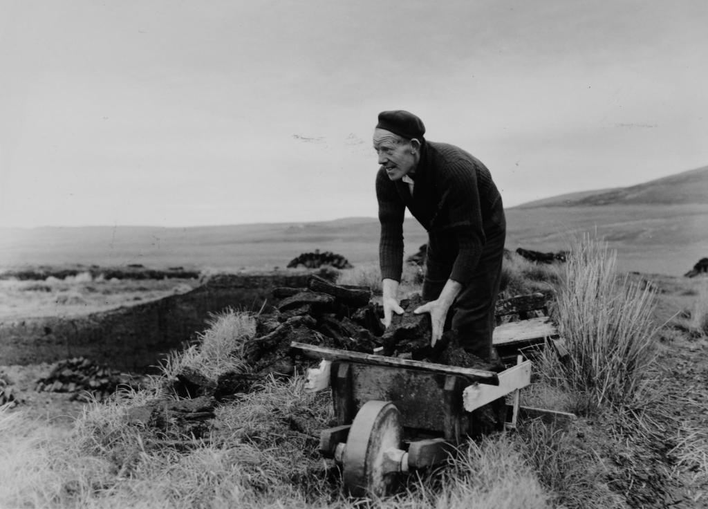 A man filling a barrow of peat in a peat bog, BELUM.Yt759