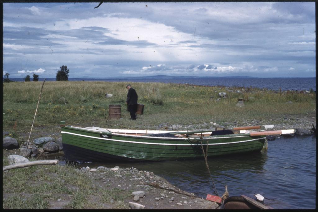 A colour photograph of a small boat on the shorts of Lough Neagh.