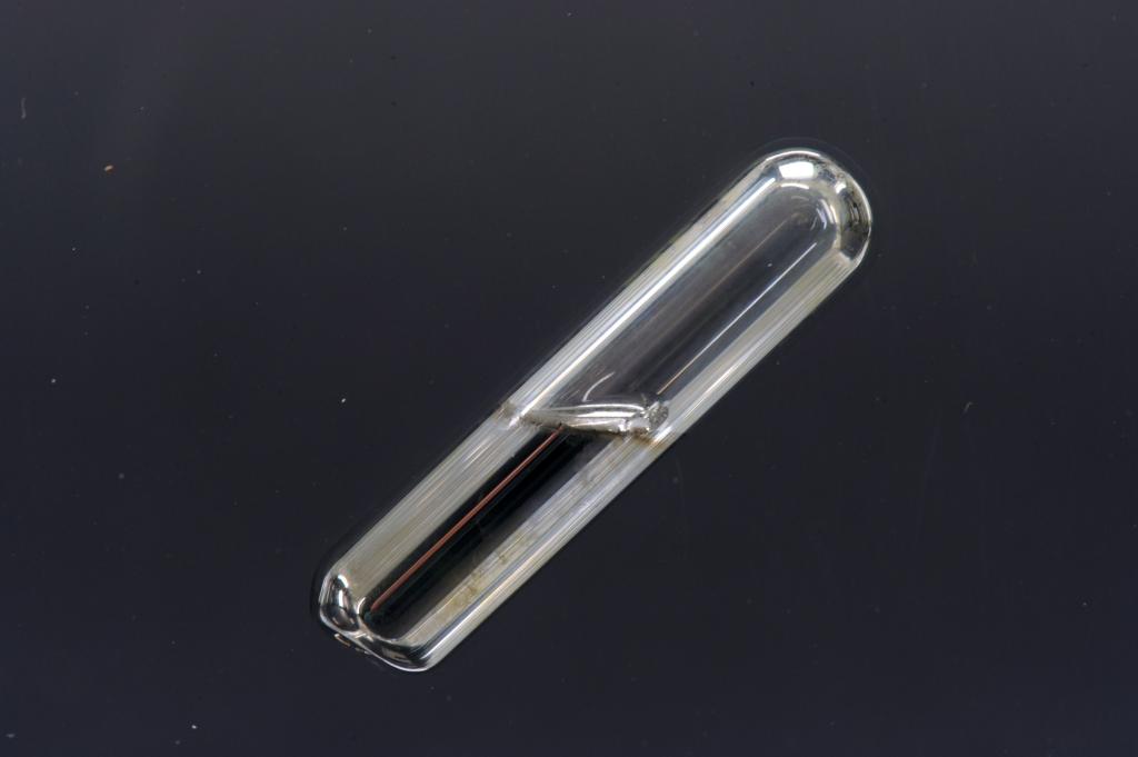 A small vial with a clearish liquid inside, half full.